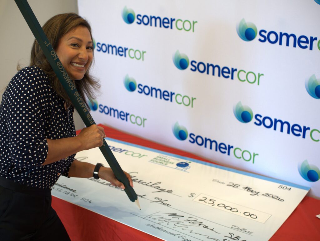 Angelica Garcilazo signing a giant check with the Big Green Pencil